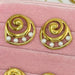 Set of gold earrings with pearls and gemstones on a pink velvet surface
