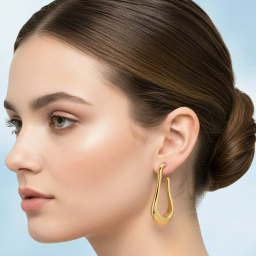 Woman wearing gold hoop earrings with a light blue background