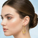Woman wearing gold hoop earrings with a light blue background