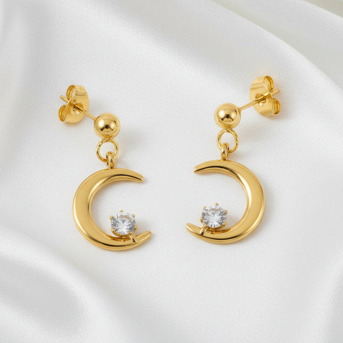 Gold earrings with moon designs and clear stones on a white background