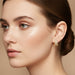 Gold hoop earrings with clear gemstones on a model
