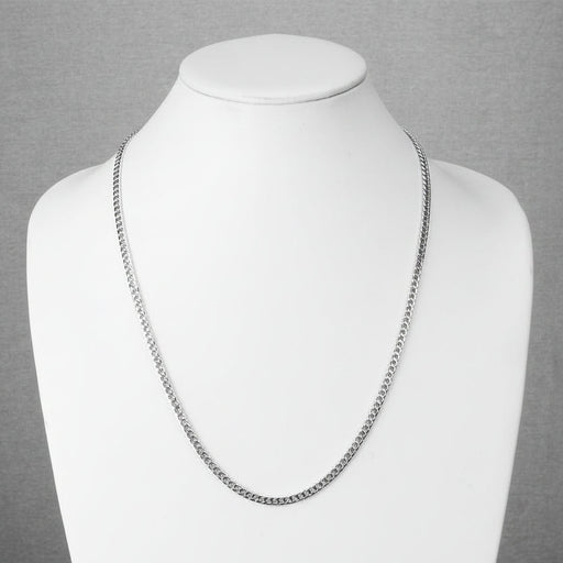 Silver chain necklace on a mannequin against a gray background