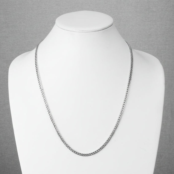 Silver chain necklace on a mannequin against a gray background