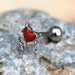 Silver barbell with a red heart-shaped stud on a stone surface