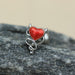 Red heart-shaped pendant with silver design on a stone surface
